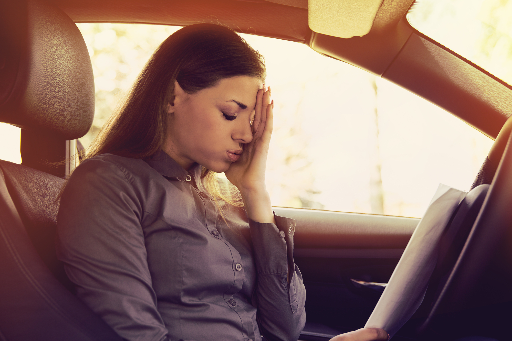 Reckless Driving Vs. Speeding Ticket - Stressed woman driver with papers sitting inside her car